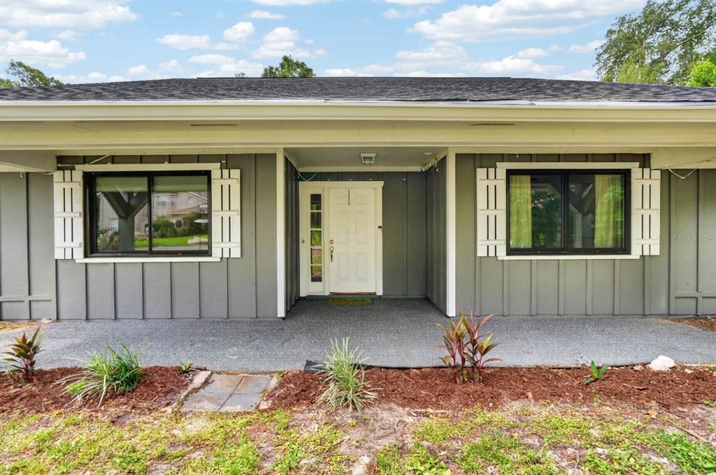 The exterior of a single-story house features gray vertical siding, white shutters, and a porch — 11 RIO PINAR TRAIL, ORMOND BEACH, FL