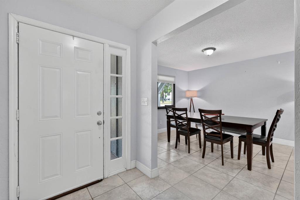 An entryway with a white front door leads into a dining room with tiled floors — 11 RIO PINAR TRAIL, ORMOND BEACH, FL