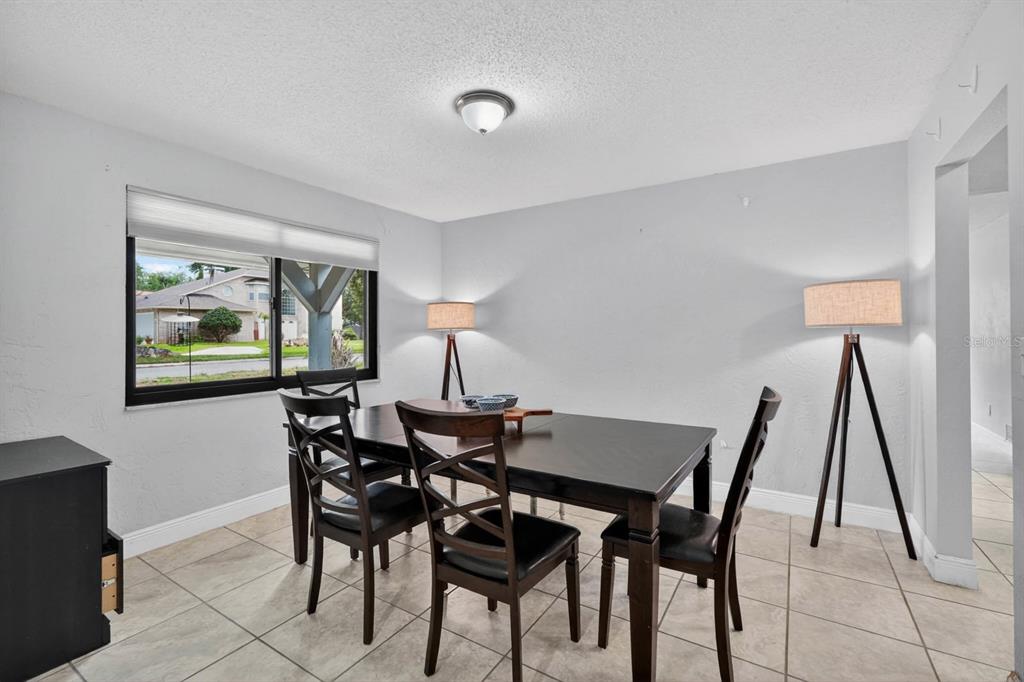 A dining room features a dark wood table, four chairs, tile flooring, and two floor lamps — 11 RIO PINAR TRAIL, ORMOND BEACH, FL