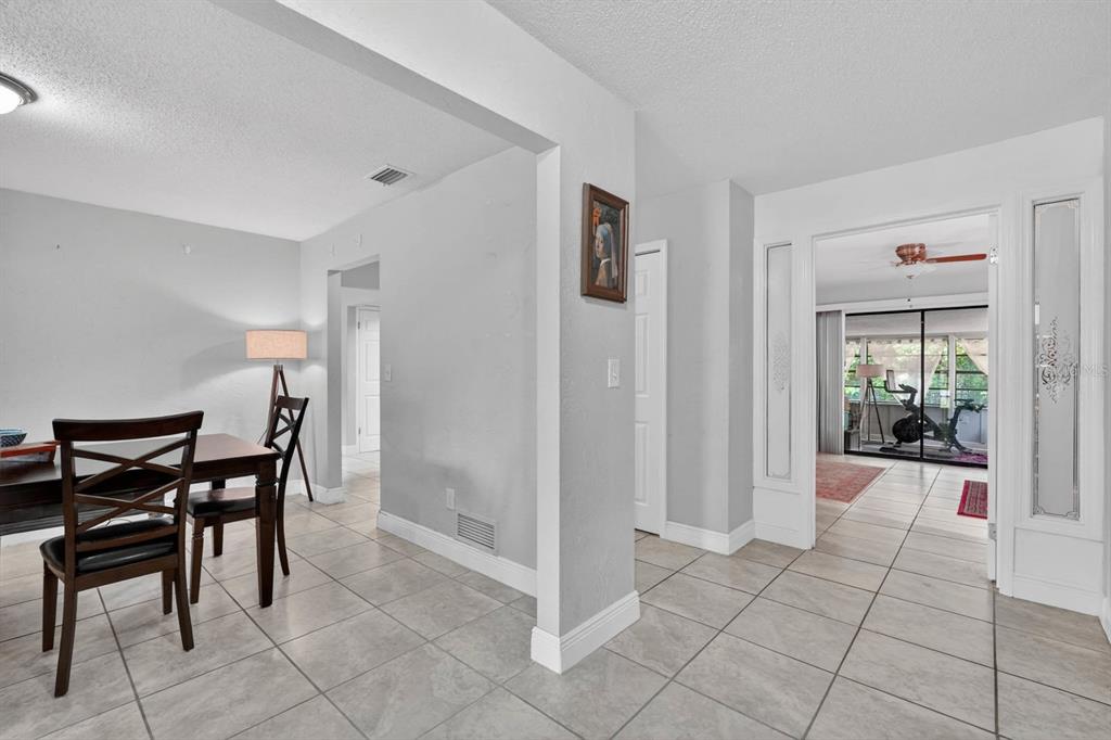 A dining area with tile floors opens into a living space with a sliding glass door — 11 RIO PINAR TRAIL, ORMOND BEACH, FL