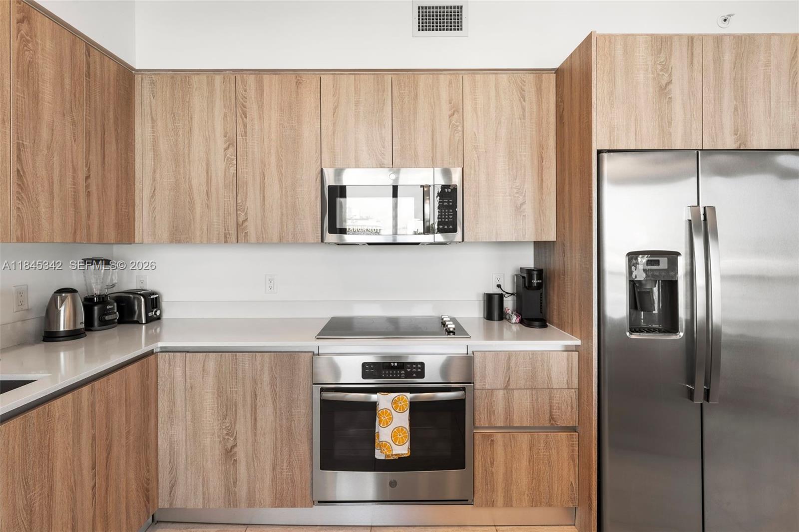 A kitchen features light wood cabinets, stainless steel appliances, and white countertops — 3900 Biscayne Blvd # 400, Miami FL 33137, MIAMI, FL