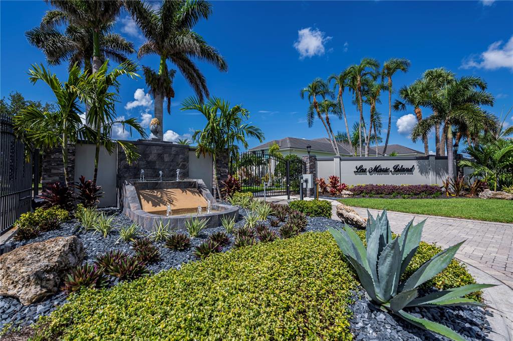 The gated entrance of Lea Marie Island features a stone fountain, palm trees, and landscaping — 4041 LEA MARIE ISLAND DRIVE, PORT CHARLOTTE, FL
