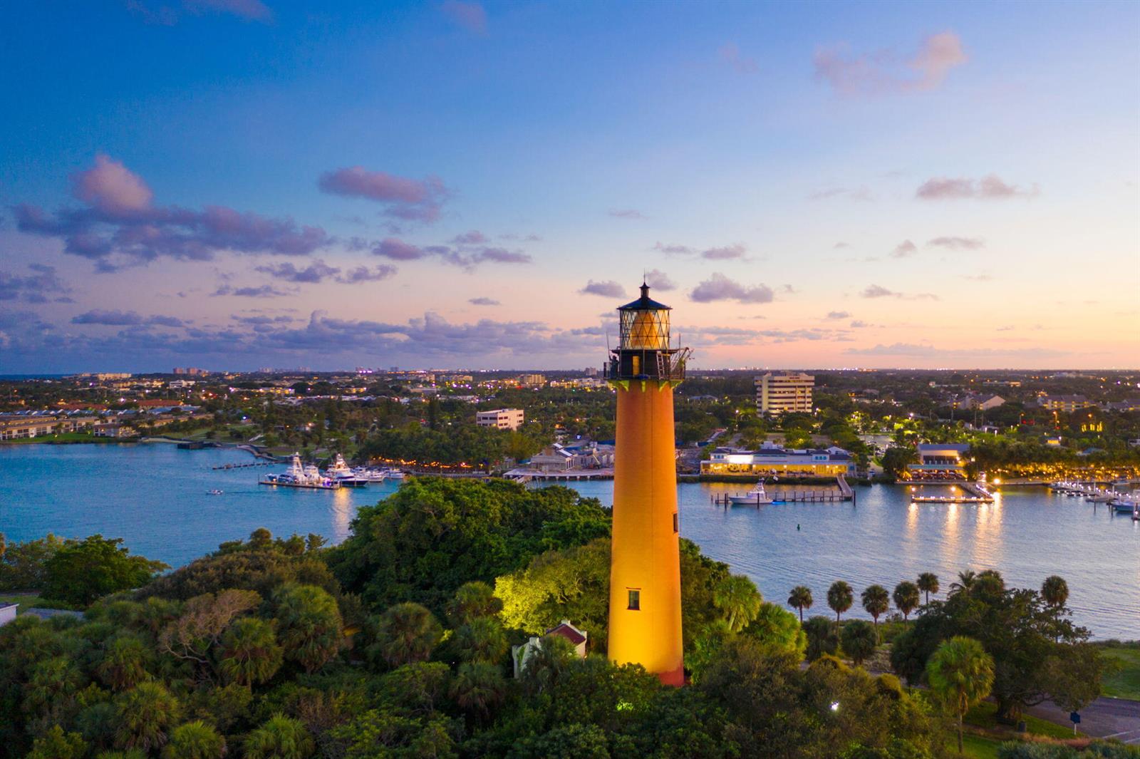 An aerial view of the Jupiter Inlet Lighthouse illuminated at sunset near a coastal waterway — 48 Live Oak Circle, Jupiter FL 33469, JUPITER, FL