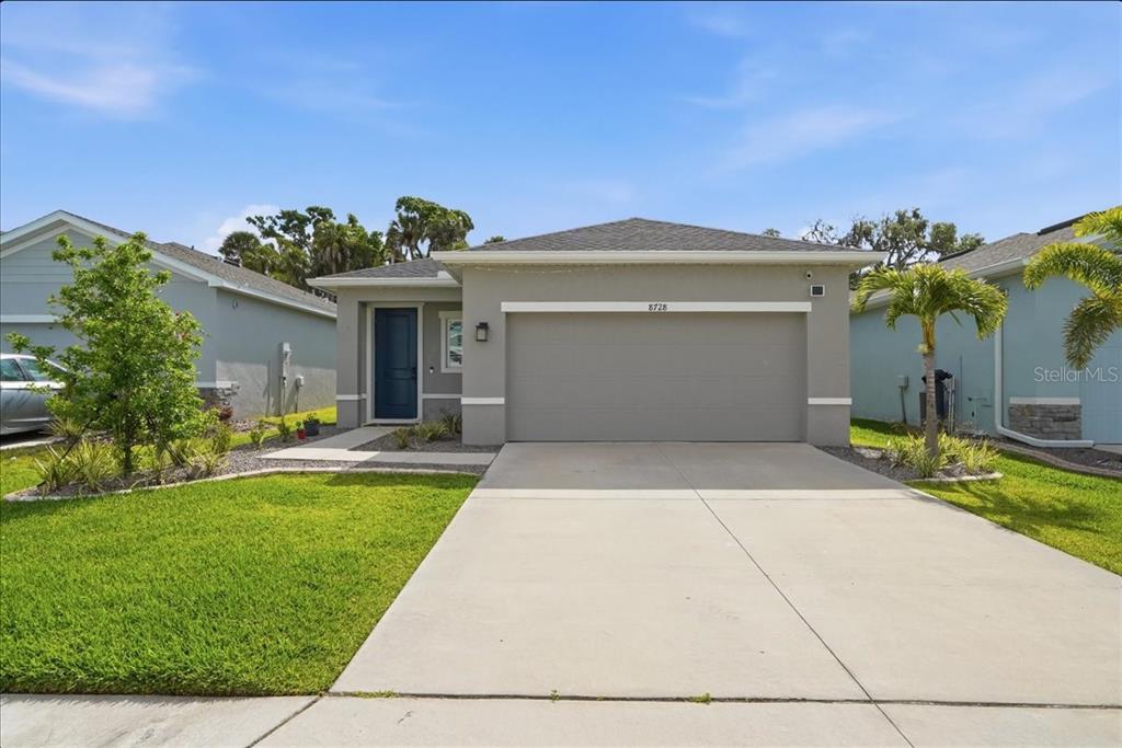 A single-story house with a gray stucco exterior, a two-car garage, and a blue door — 8728 STARRY NIGHT TERRACE, PARRISH, FL
