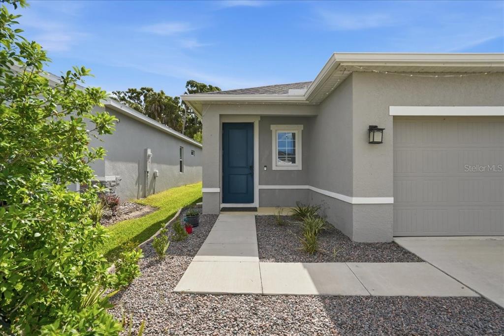 The exterior of a gray house features a blue front door and a concrete walkway — 8728 STARRY NIGHT TERRACE, PARRISH, FL