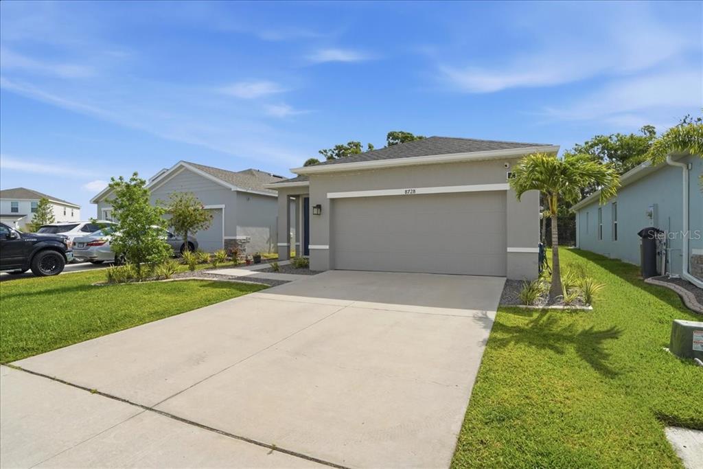 A single-story suburban house with a gray exterior, a two-car garage, and a concrete driveway — 8728 STARRY NIGHT TERRACE, PARRISH, FL