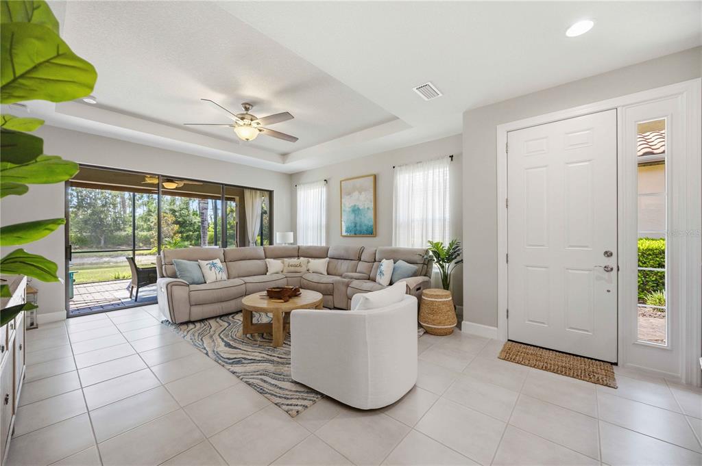 A living room features a sectional sofa, a white armchair, and a sliding glass door — 5749 SEMOLINO STREET, NOKOMIS, FL