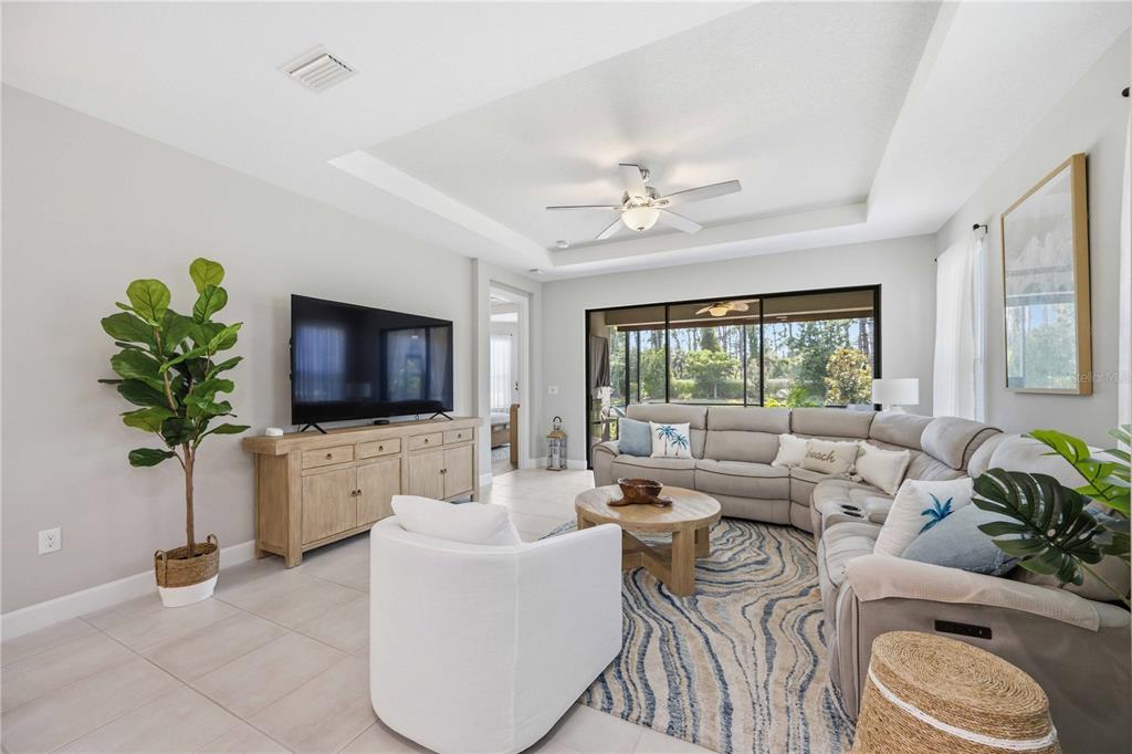 A bright living room features a large sectional sofa, a television console, and a ceiling fan — 5749 SEMOLINO STREET, NOKOMIS, FL