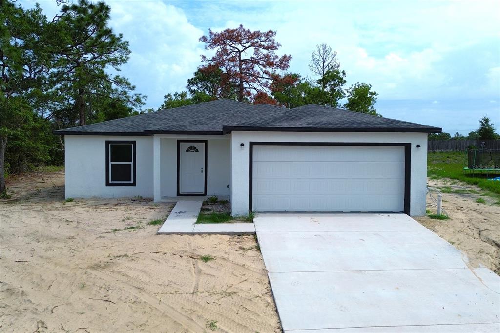 A single-story house with a white stucco exterior, dark trim, and a two-car garage — 12493 KILLIAN STREET, SPRING HILL, FL