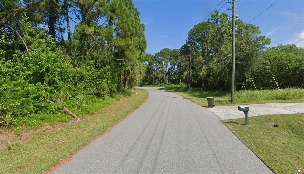 A paved road winds through a wooded residential area with a mailbox on the right — 1667 RED BUD CIRCLE NW, PALM BAY, FL