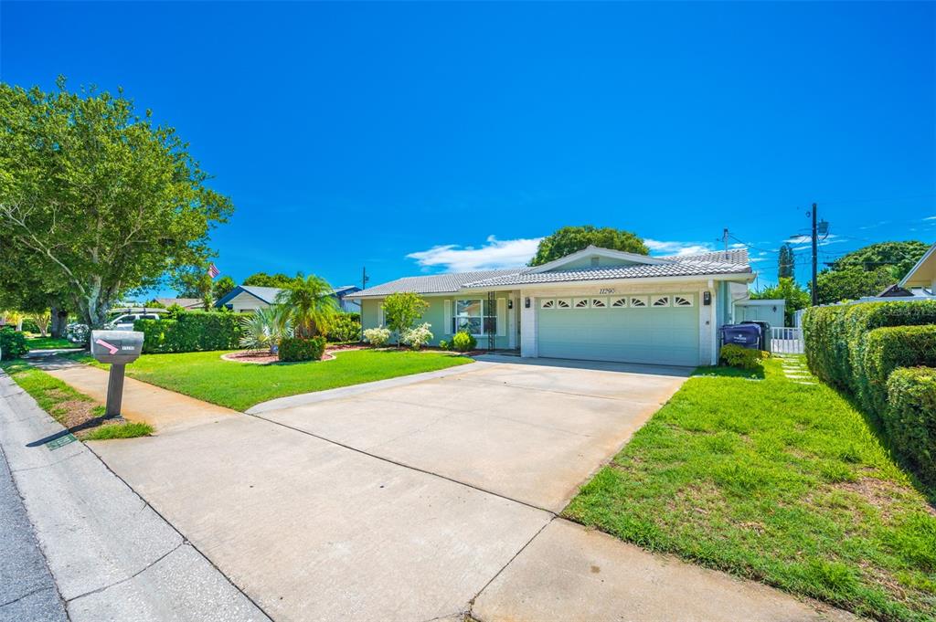 A single-story house with a light green exterior, a two-car garage, and a concrete driveway — 11290 142ND STREET, LARGO, FL