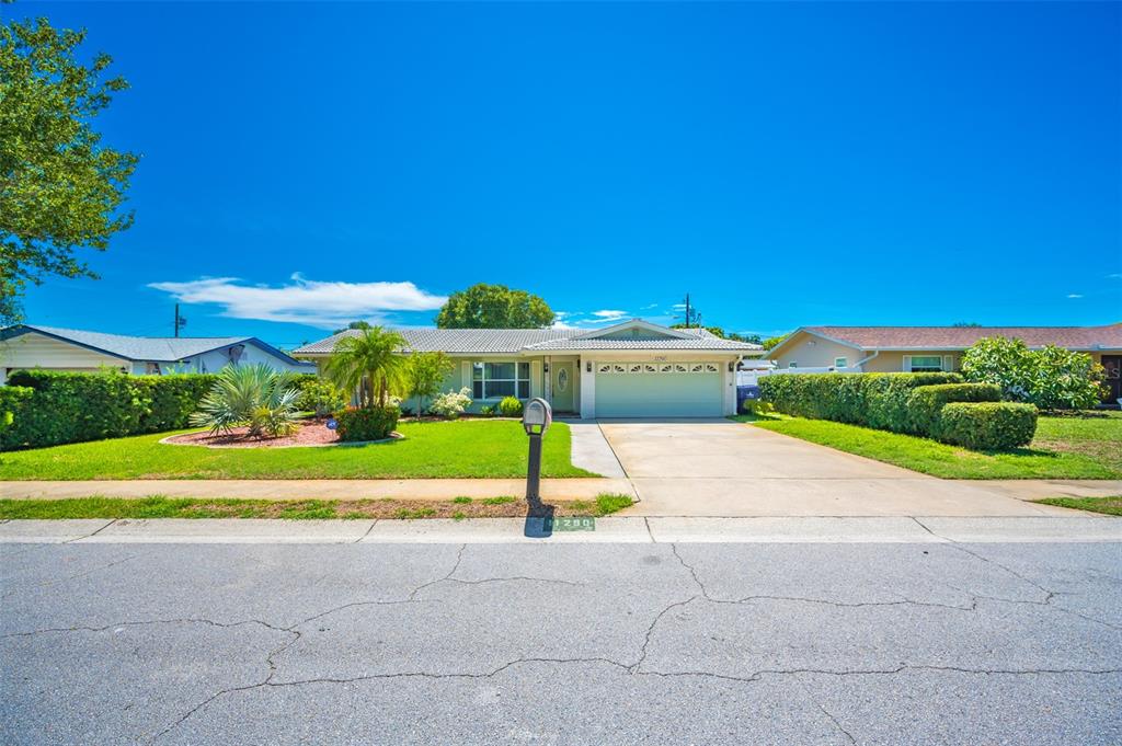 A single-story house with a light green exterior, a two-car garage, and a manicured lawn — 11290 142ND STREET, LARGO, FL
