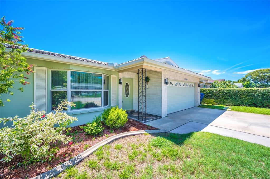 A single-story house with a light green exterior, a front porch, and a two-car garage — 11290 142ND STREET, LARGO, FL