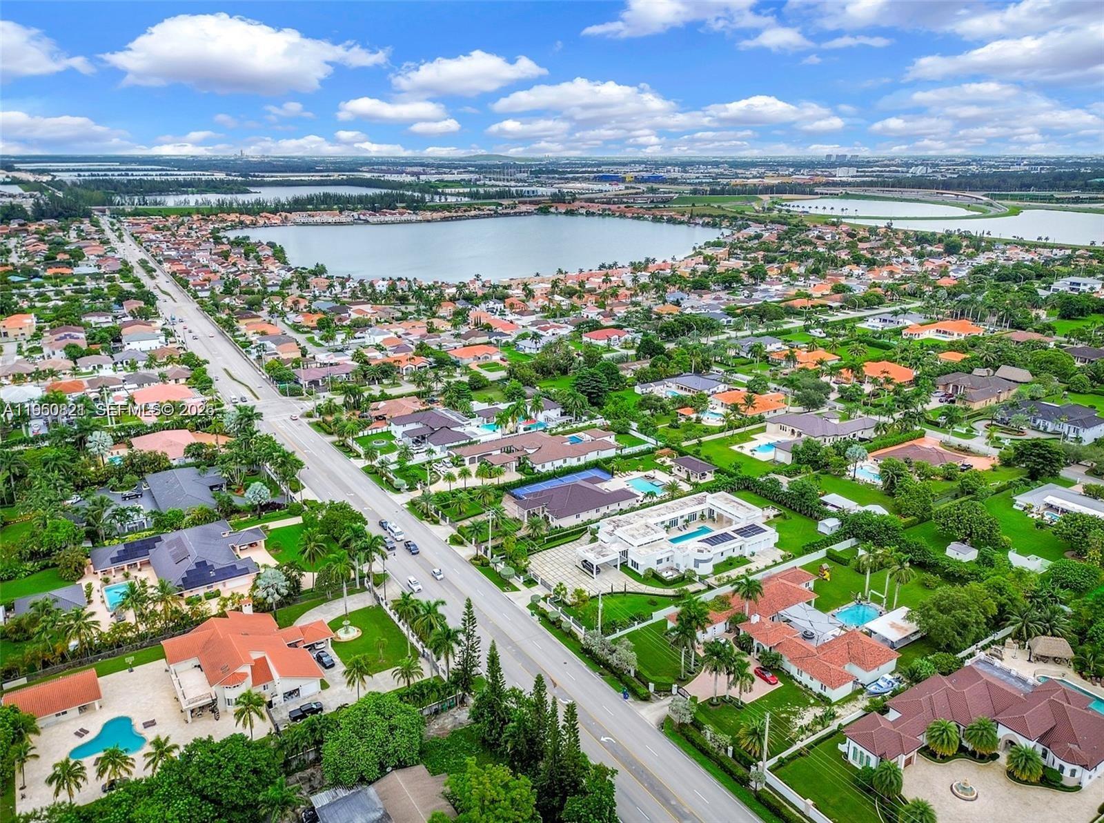 An aerial view shows a suburban neighborhood with houses, swimming pools, and a large lake — 433 NW 127th Ave, Miami FL 33182, MIAMI, FL