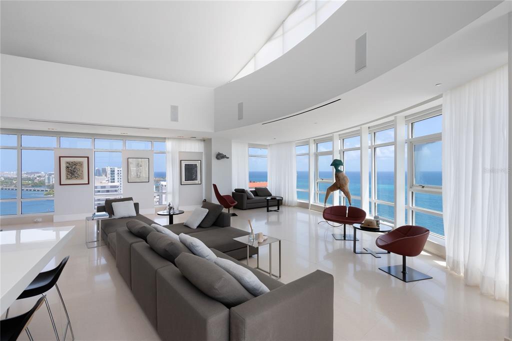 A modern, open-concept kitchen and living area features a large island, sculpture, and ocean views — 1052 ASHFORD AVENUE UNIT PH-18, SAN JUAN, PR