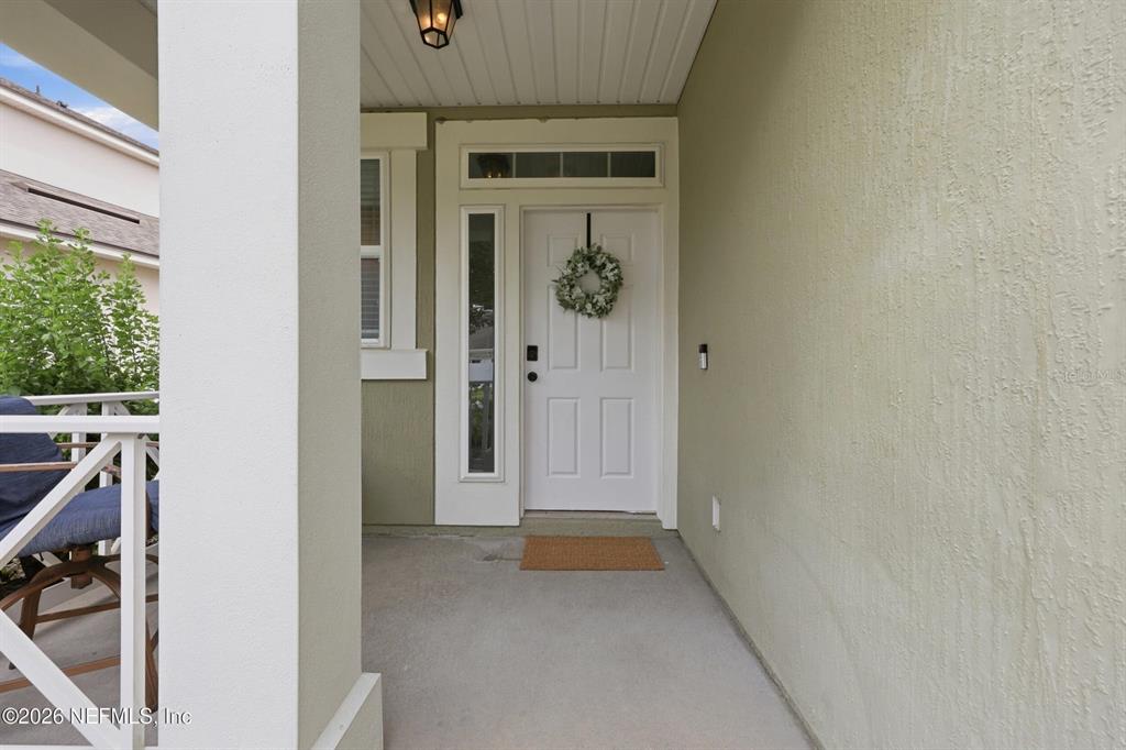 A covered front porch features a white door with a wreath and a side window — 14589 GARDEN GATE DRIVE, JACKSONVILLE, FL