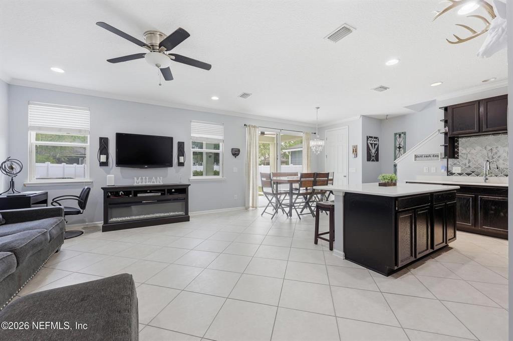 An open-concept living room and kitchen featuring tile flooring, a dark island, and a television — 14589 GARDEN GATE DRIVE, JACKSONVILLE, FL