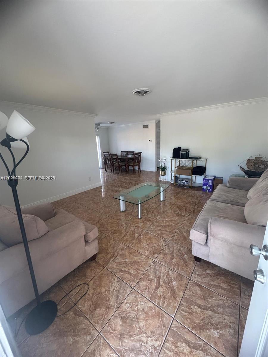 A living room features beige sofas, a glass coffee table, and brown tile flooring — 2801 NW 183rd St, Miami Gardens FL 33056, MIAMI GARDENS, FL