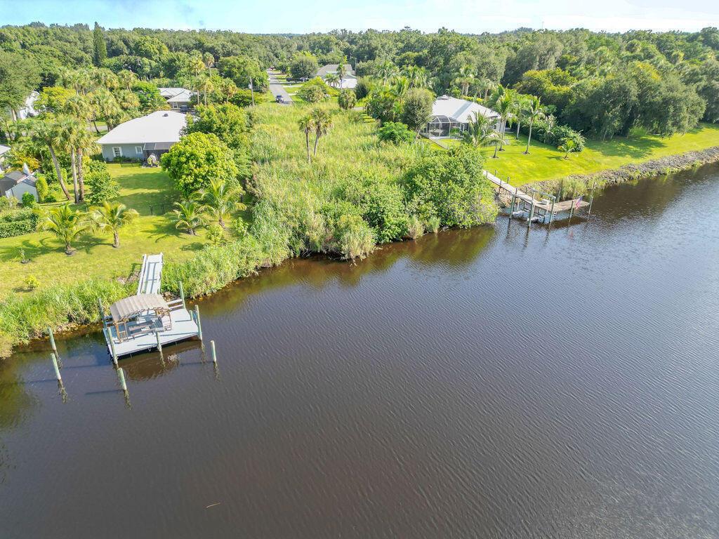 An aerial view shows a waterfront property with two docks, a grassy yard, and dense vegetation — 15340 SW Palm Drive, FL 34956, FL
