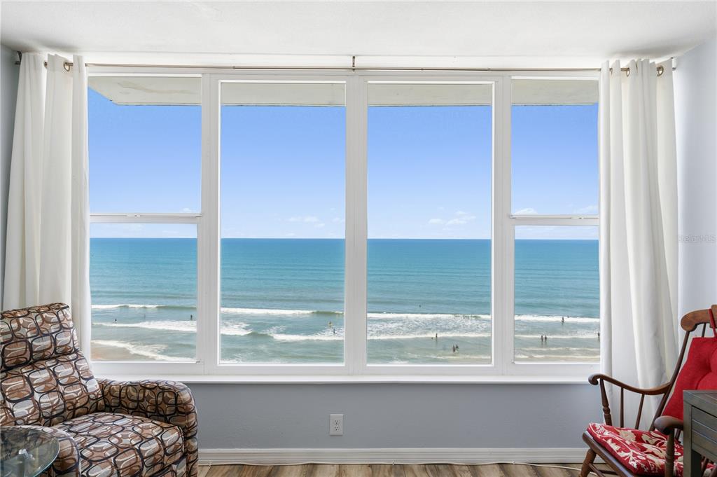 A room with a large window overlooking the ocean, flanked by white curtains and chairs — 2800 N ATLANTIC AVENUE UNIT 715, DAYTONA BEACH, FL
