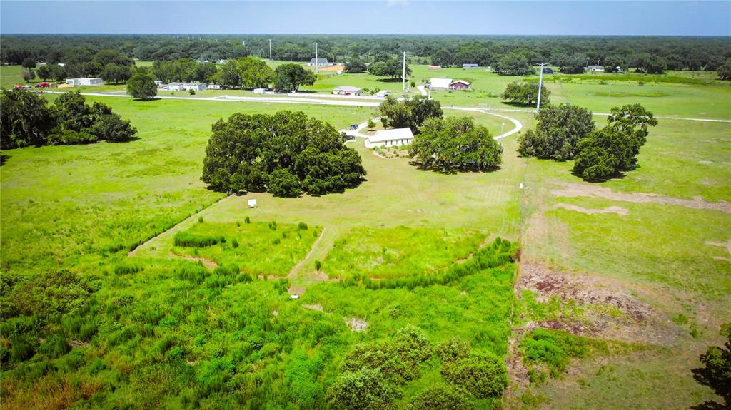 An aerial view shows a rural property with a house, large trees, and open fields — 7820 SW 32ND STREET, BUSHNELL, FL