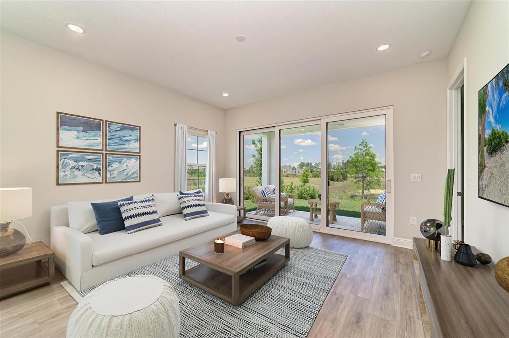 A living room features a white sofa, wood coffee table, and sliding glass doors to a patio — 35509 STABLETON LANE, ZEPHYRHILLS, FL