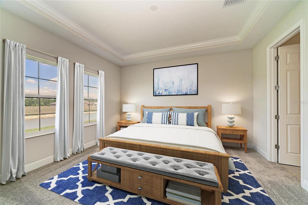A bedroom features a wooden bed frame, a tufted bench, and windows overlooking a pond — 35509 STABLETON LANE, ZEPHYRHILLS, FL