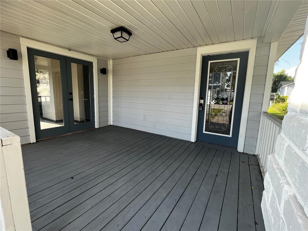 A covered wooden deck features gray siding, a glass-paneled door, and double French doors — 402 E EMMA STREET, TAMPA, FL