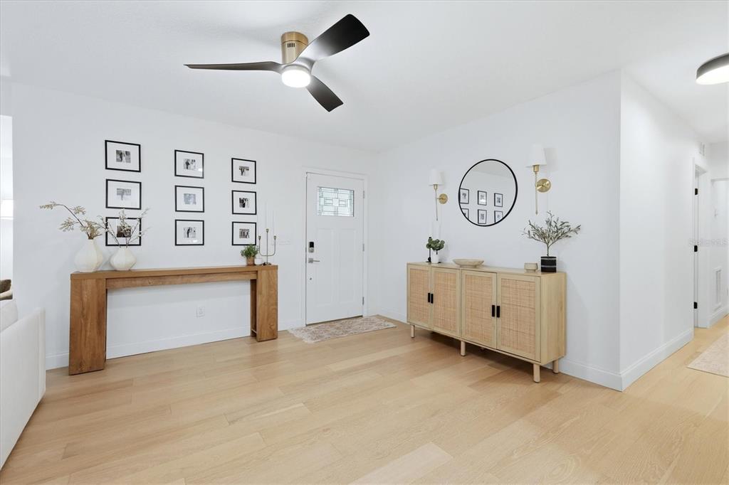 An entryway features light wood flooring, a console table, a sideboard, and wall-mounted artwork — 6291 63RD STREET N, PINELLAS PARK, FL