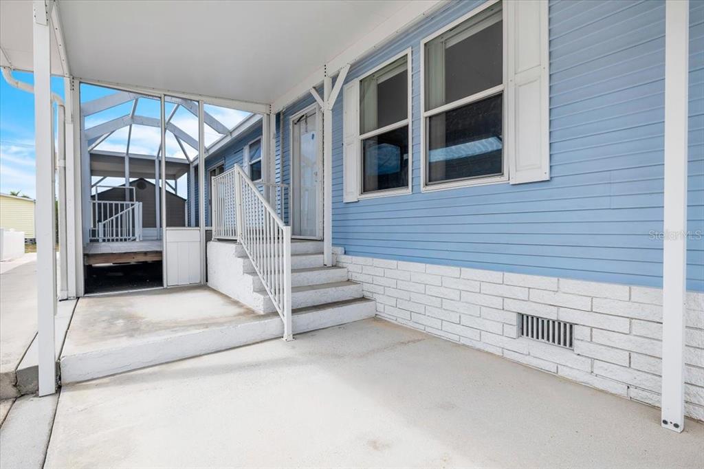 A blue mobile home exterior features a concrete patio, white stairs, and a screened enclosure — 3650 ROSSMERE ROAD, PORT CHARLOTTE, FL