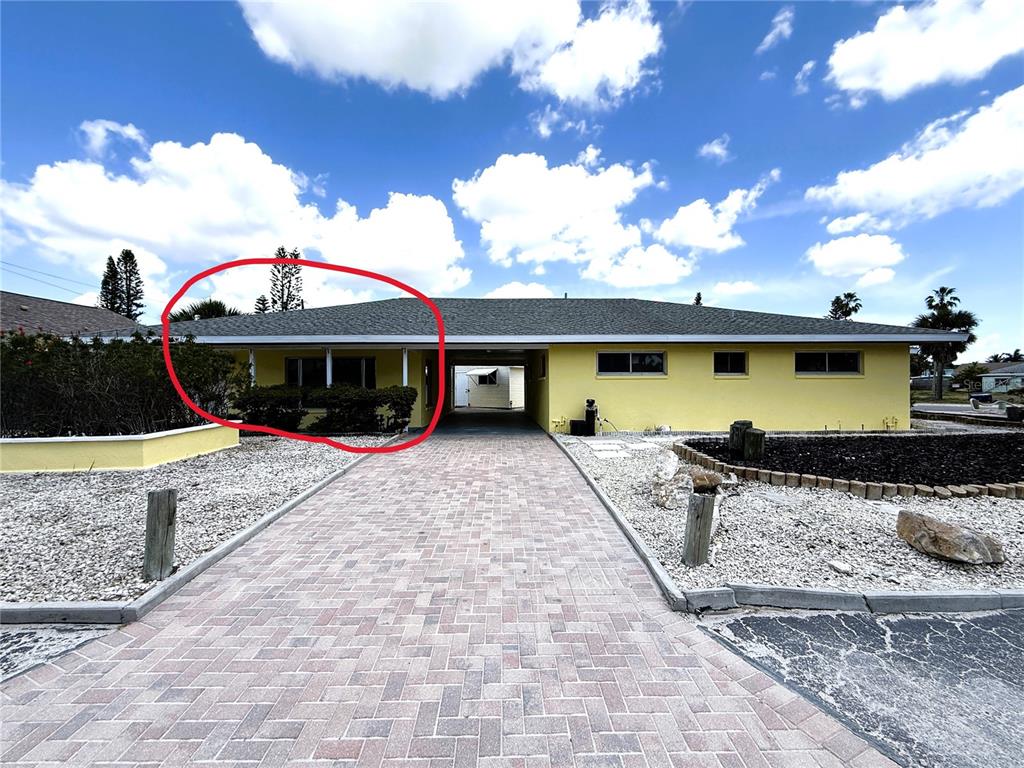 The exterior of a yellow house features a brick driveway and a covered carport — 14017 W PARSLEY DRIVE, MADEIRA BEACH, FL