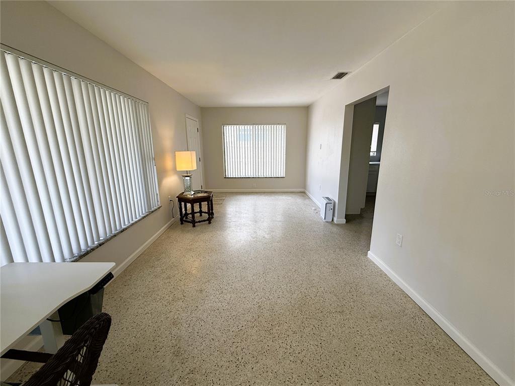 A living room with light walls, vertical blinds, and speckled flooring — 14017 W PARSLEY DRIVE, MADEIRA BEACH, FL