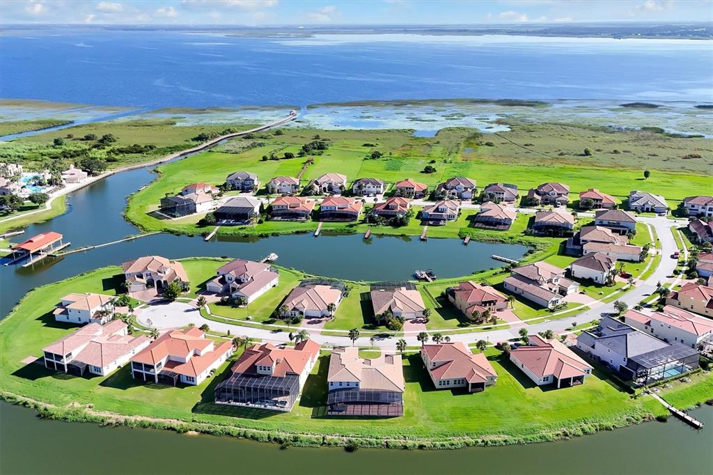 An aerial view shows a suburban neighborhood of houses surrounding a small lake — 870 SPINNAKER WAY, KISSIMMEE, FL