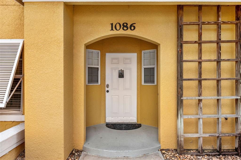 A yellow stucco exterior features a white front door under an arched entryway with 1086 — 1086 PARK RIDGE CIRCLE, KISSIMMEE, FL