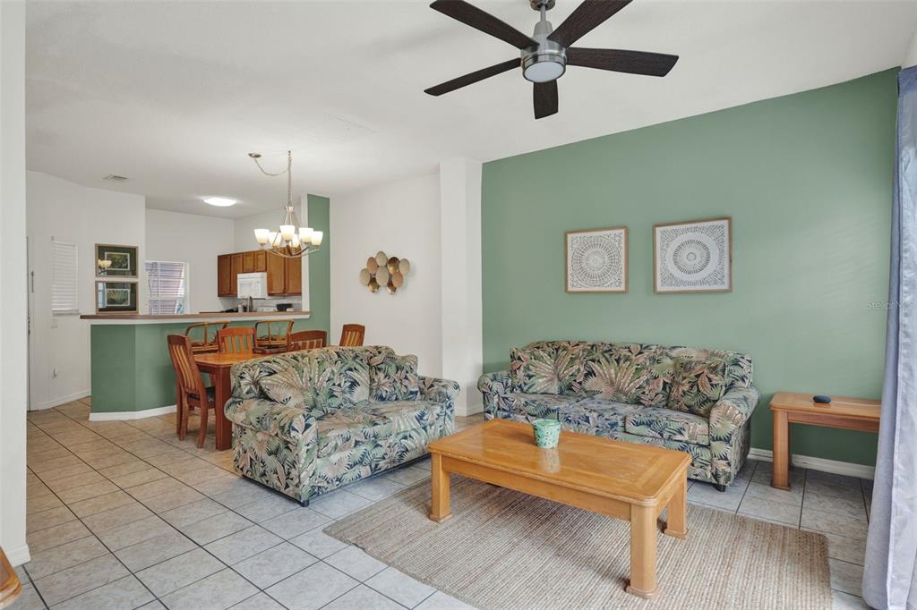 A living room and dining area feature tile floors, a green accent wall, and floral sofas — 1086 PARK RIDGE CIRCLE, KISSIMMEE, FL