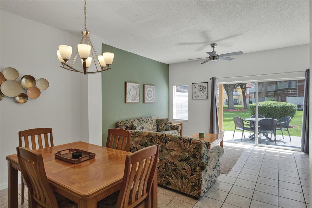 A dining area and living room with tile floors, a green accent wall, and patio access — 1086 PARK RIDGE CIRCLE, KISSIMMEE, FL