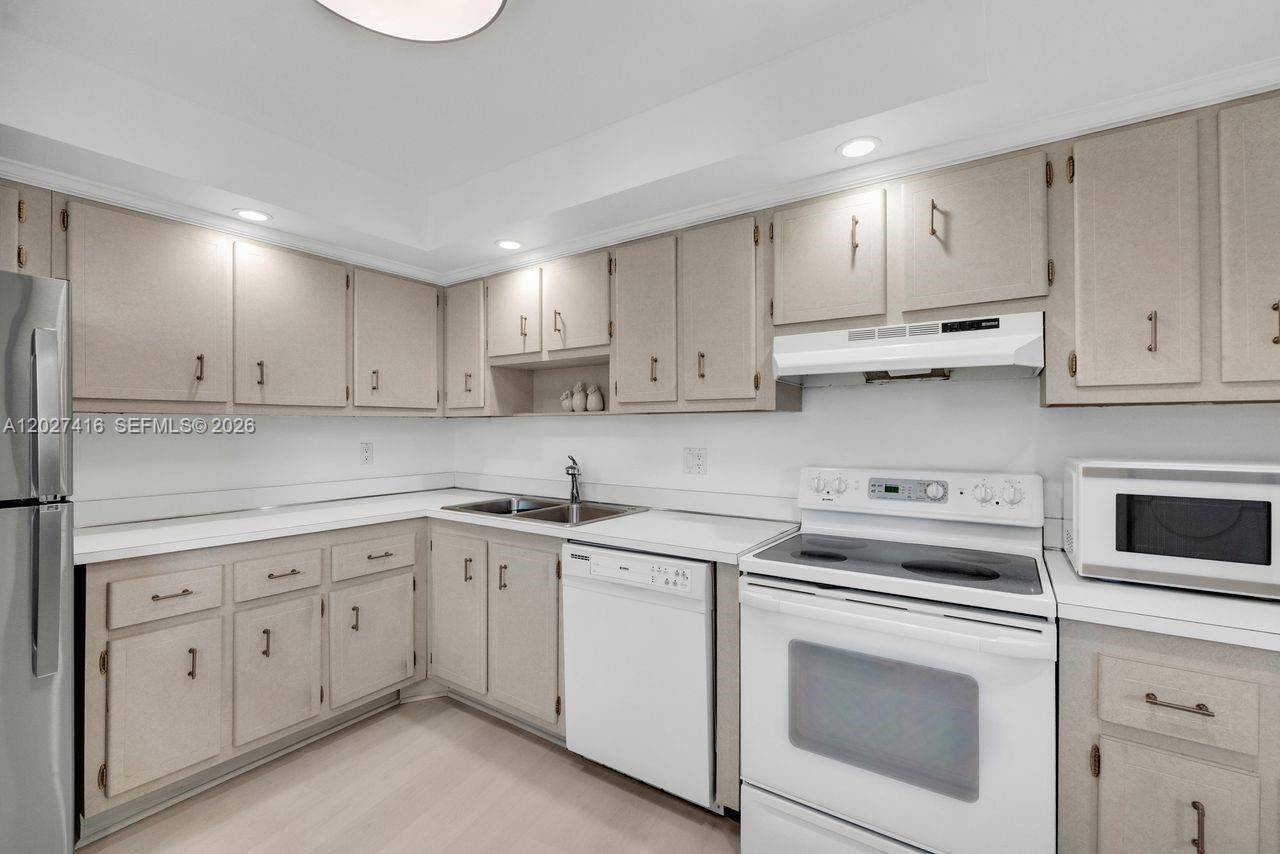 A kitchen features light-colored cabinets, white appliances, and a double-basin sink — 200 Ocean Trail Way # 1108, Jupiter FL 33477, JUPITER, FL