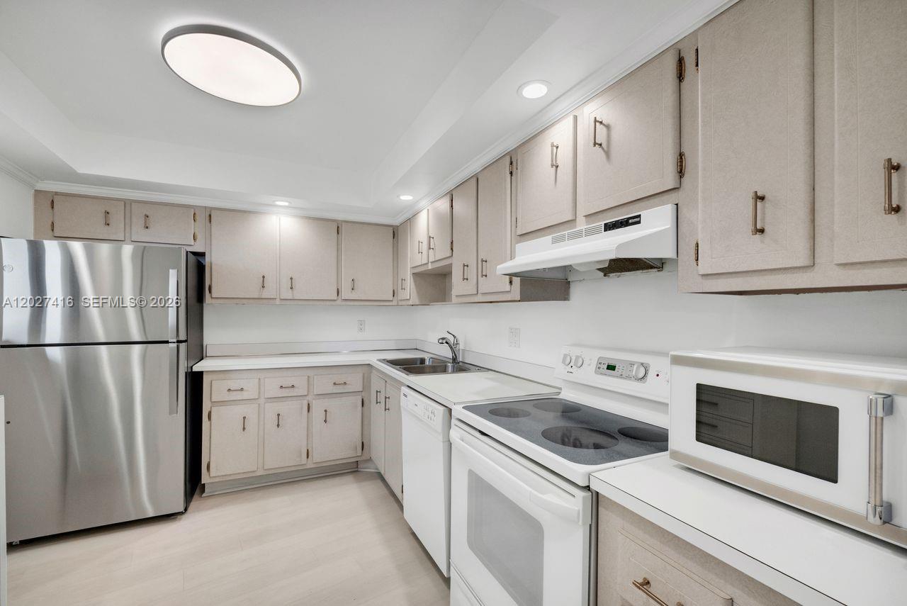 A kitchen features light-colored cabinets, white appliances, a stainless steel refrigerator, and light wood flooring — 200 Ocean Trail Way # 1108, Jupiter FL 33477, JUPITER, FL