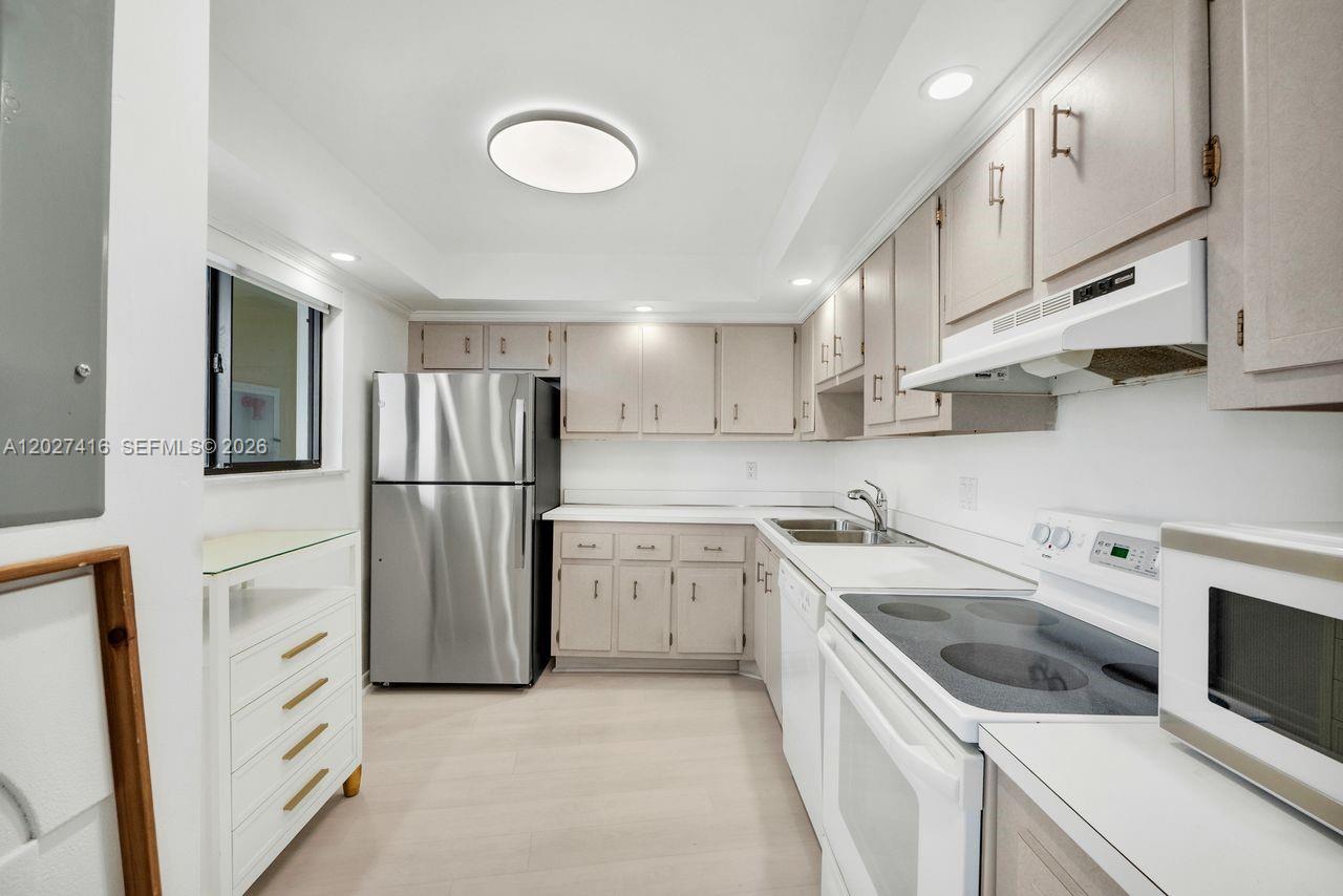 A kitchen features light-colored cabinetry, stainless steel appliances, white countertops, and light wood-look flooring — 200 Ocean Trail Way # 1108, Jupiter FL 33477, JUPITER, FL