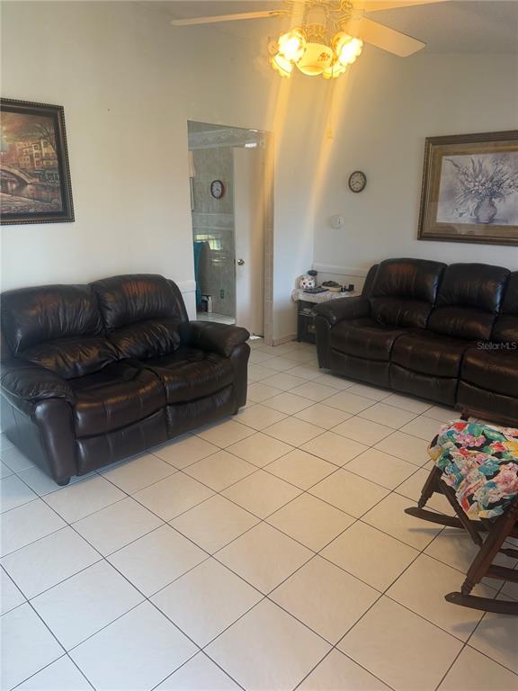 A living room features two dark leather sofas, tiled floors, and a ceiling fan — 1304 DONWOODS LANE, ROYAL PALM BEACH, FL