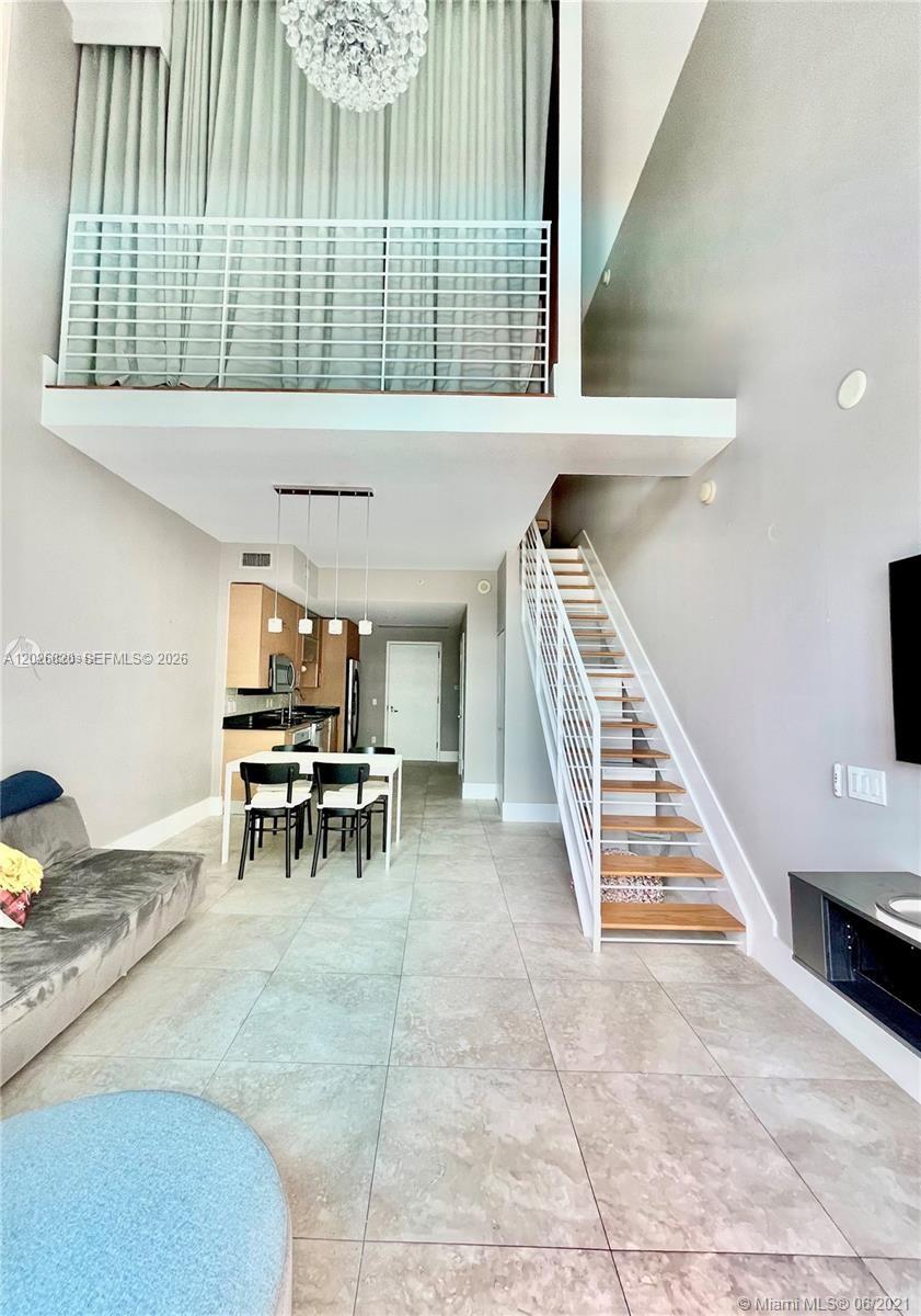 A living room and kitchen area features a loft level, staircase, and tile flooring — 60 SW 13th St # 2002, Miami FL 33130, MIAMI, FL