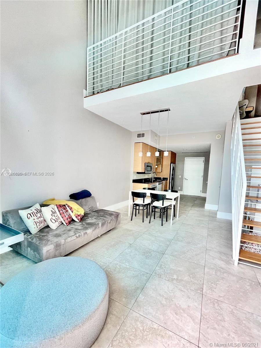 This living area features high ceilings, a lofted balcony, tile flooring, and an open kitchen — 60 SW 13th St # 2002, Miami FL 33130, MIAMI, FL