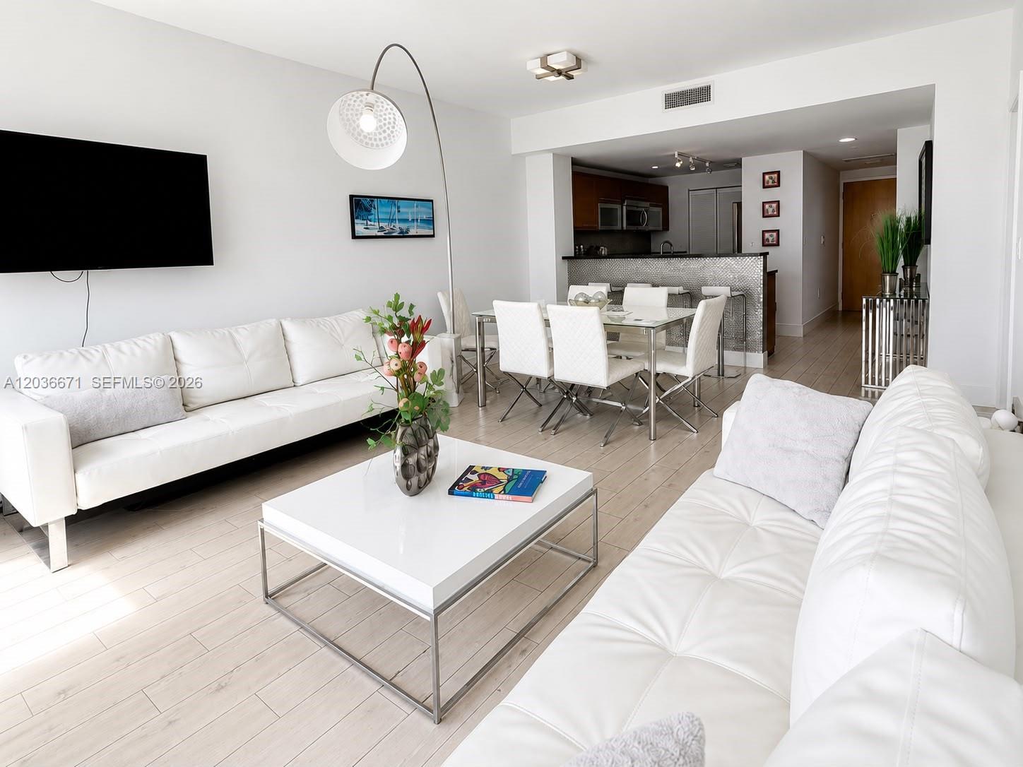 A bright living and dining area features white leather sofas, a glass table, and light flooring — 253 NE 2nd St # 3004, Miami FL 33132, MIAMI, FL