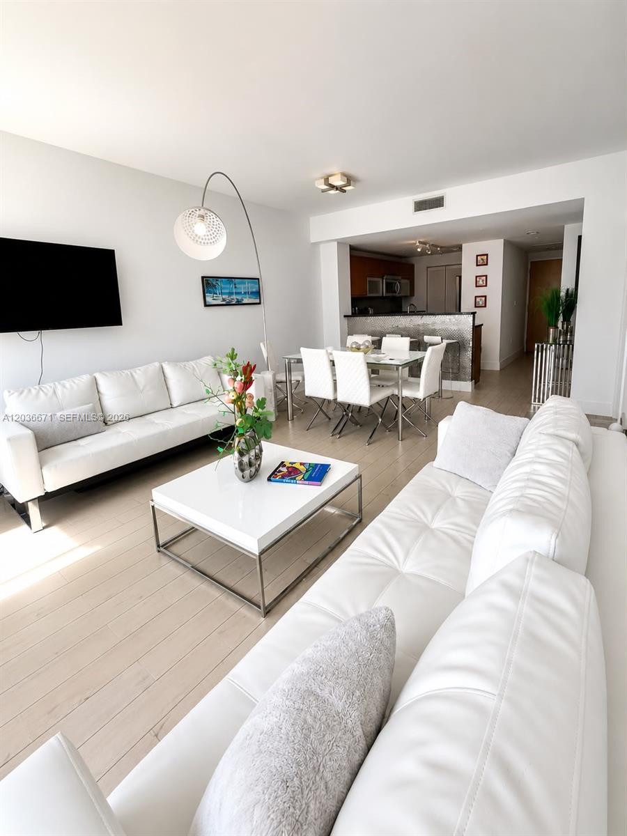 A living room and dining area feature white leather sofas, a coffee table, and flooring — 253 NE 2nd St # 3004, Miami FL 33132, MIAMI, FL