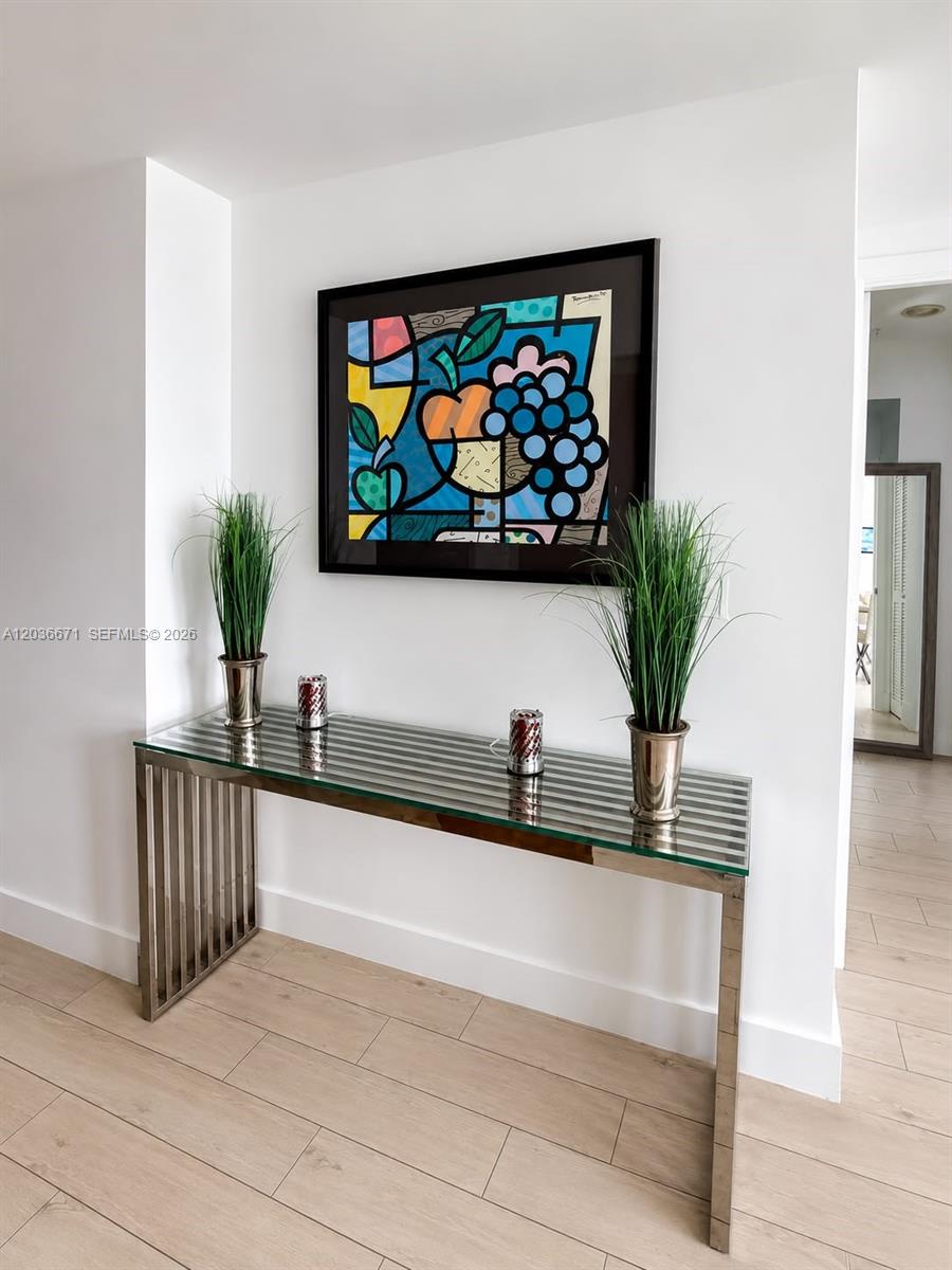 A glass-topped console table with metal legs sits against a white wall beneath framed art — 253 NE 2nd St # 3004, Miami FL 33132, MIAMI, FL