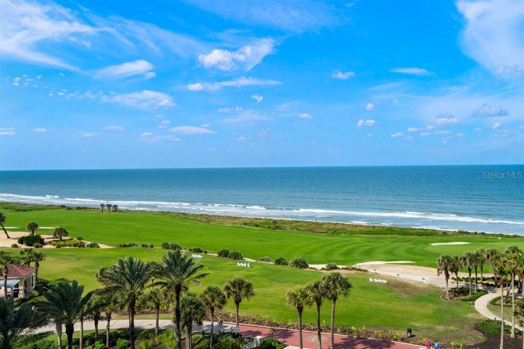 An elevated view of a grassy golf course bordering the ocean under a blue sky — 200 OCEAN CREST DRIVE UNIT 713, PALM COAST, FL