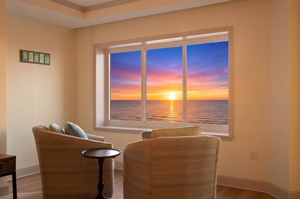 Two armchairs face a large window overlooking a sunset over the ocean — 200 OCEAN CREST DRIVE UNIT 713, PALM COAST, FL