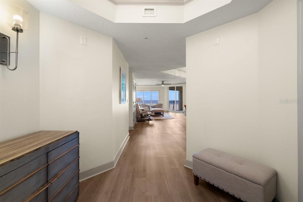 A hallway with light wood flooring leads toward a living area with ocean views — 200 OCEAN CREST DRIVE UNIT 713, PALM COAST, FL