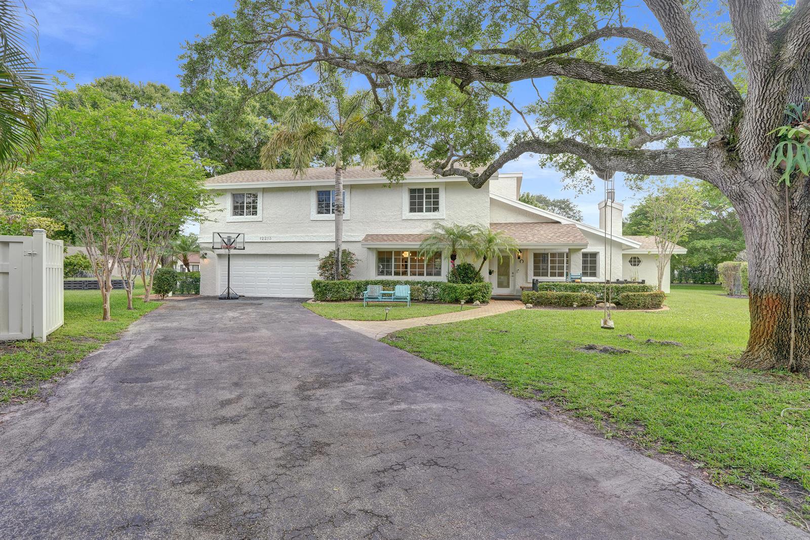 A two-story house with a white stucco exterior, a paved driveway, and a large oak tree — 12213 Melissa Way, Cooper City FL 33026, COOPER CITY, FL