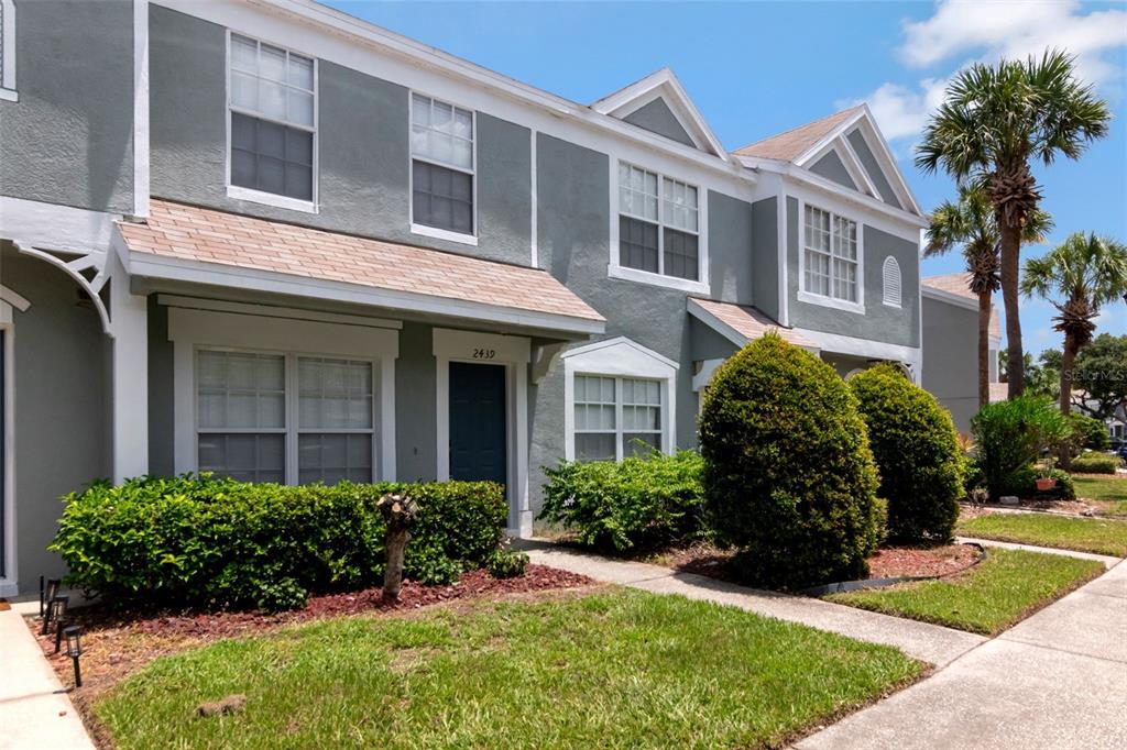 A two-story gray townhouse with a front lawn, landscaping, and a sidewalk — 2439 LAKE WOODBERRY CIRCLE, BRANDON, FL